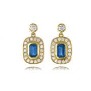 Gold earrings with blue gemstones and clear stones on a white background