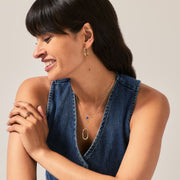 Woman wearing a blue denim top and gold jewellery against a neutral background
